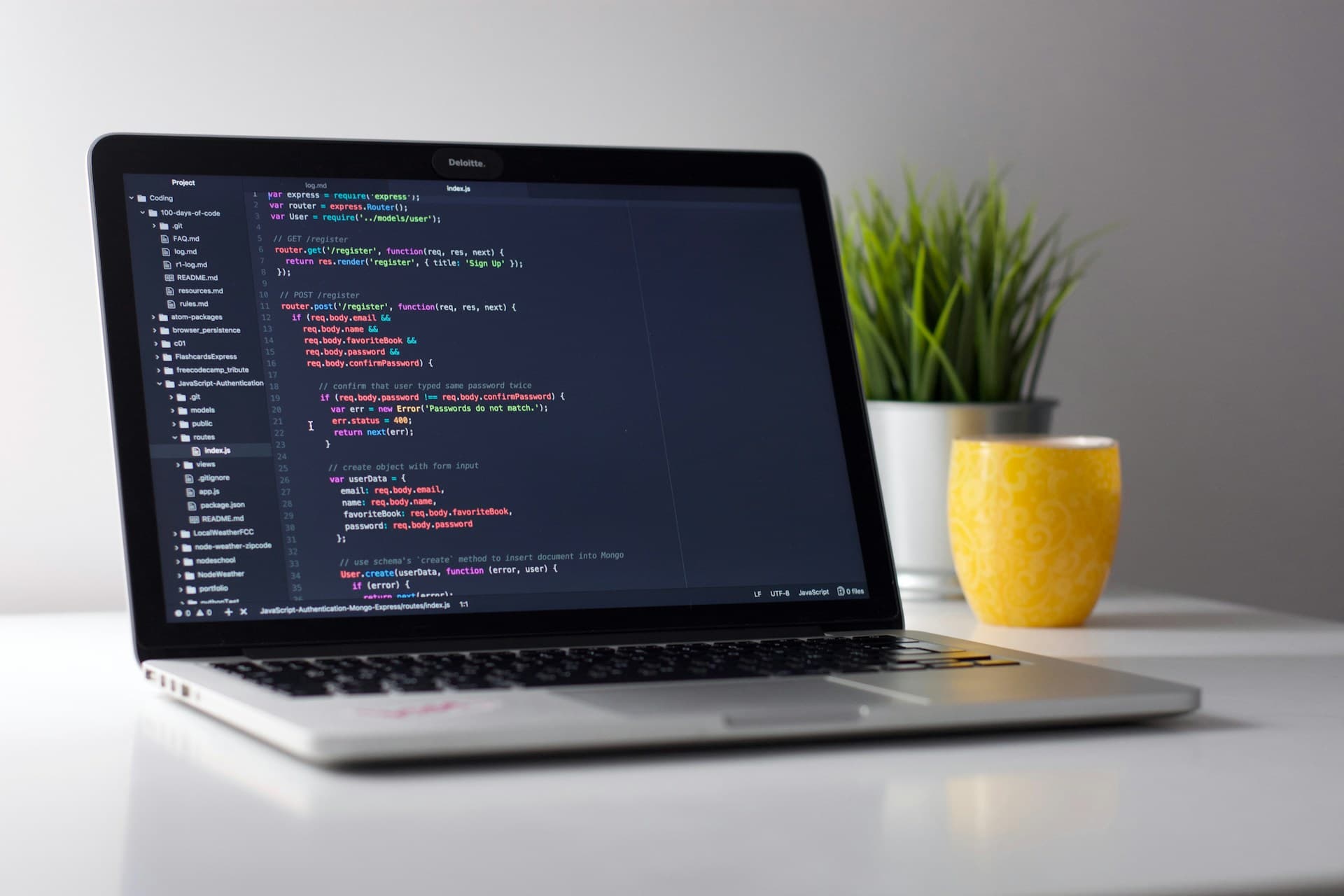 Person coding at a desk with laptop and monitors